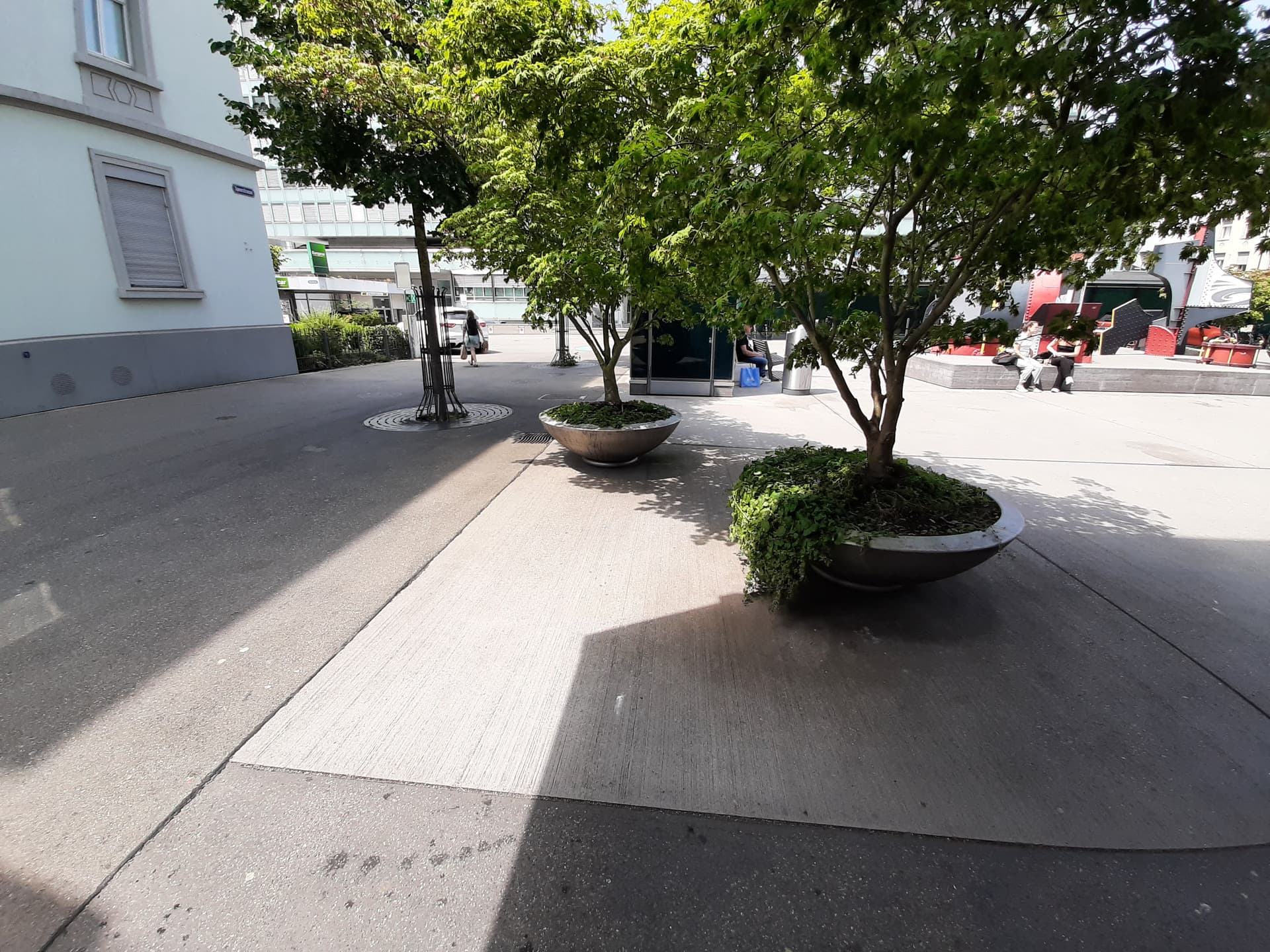 Versiegelter Platz mit Bäumen in Pflanzkübeln.