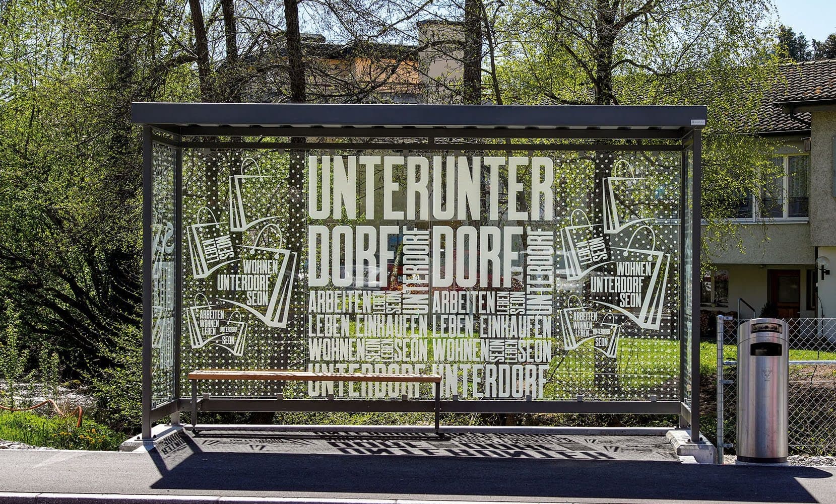 Ein Wartehäuschen ist über und über mit weisser Folie in Form von Punkten und Schrift bedeckt.