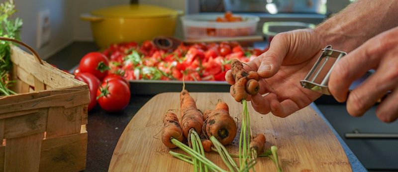 Karotten und Tomaten in der Küche schälen