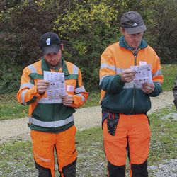 Zwei Männer in orangen Uniformen betrachten eine Broschüre.