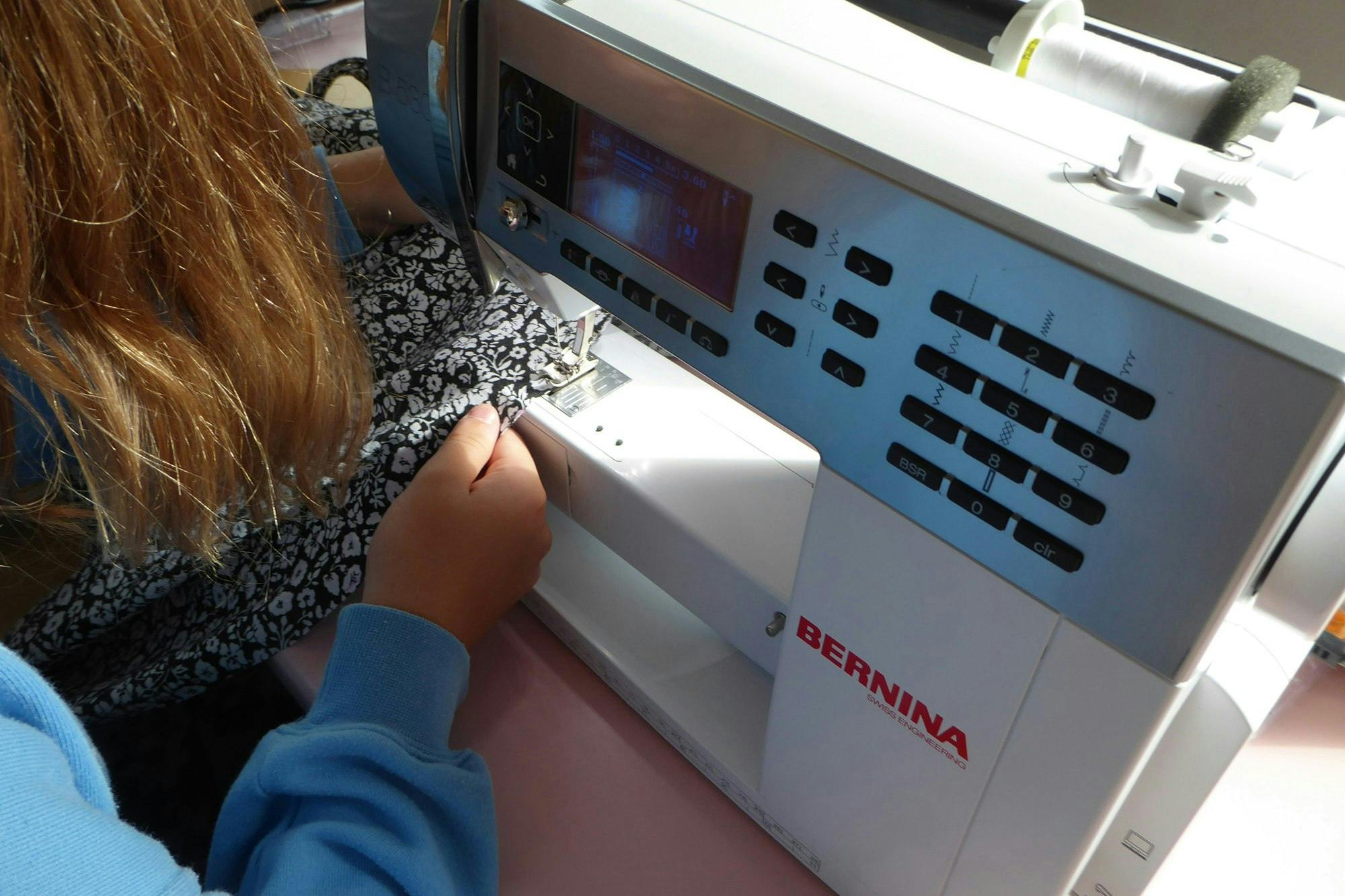 Kind arbeitet mit einer Nähmaschine.