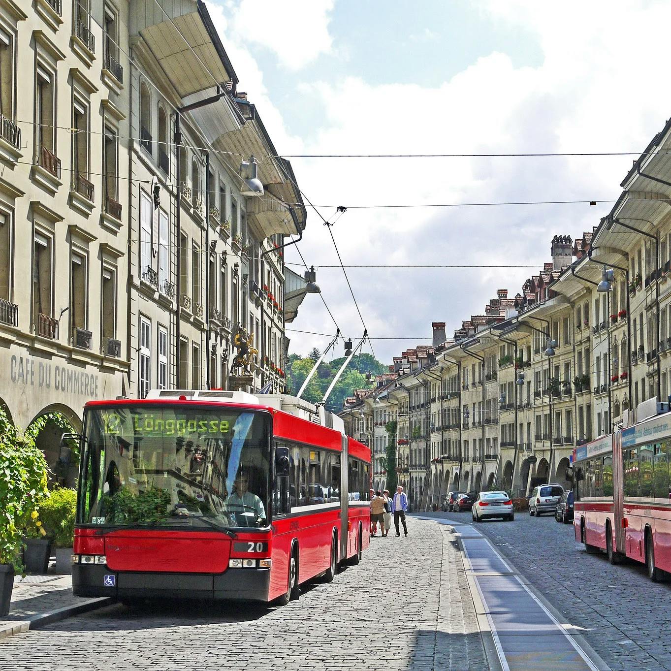 Zwei Busse stehen in einer Strasse in der Altstadt von Bern auf der linken und rechten Strassenseite.