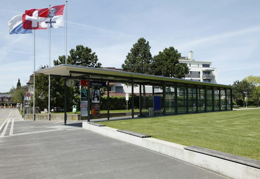 Bahnhofansicht Opfikon mit Gemeinde- und Schweizer Flagge